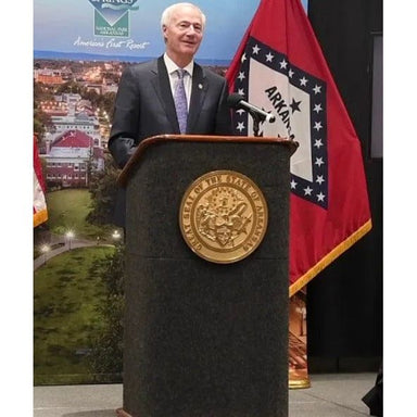 man giving a speech behind carpeted podium